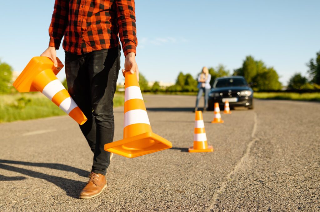 Male instructor puts cones on road, driving school
